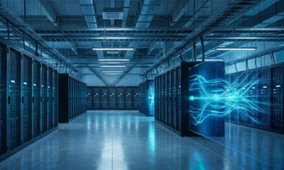 A wide, clean photograph inside a modern data center aisle with rows of server racks under cool blue lighting. On the right, blue neon energy light trails emanate from a server, representing flowing data and scalable AI infrastructure.