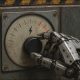 AI-generated image (GPT-2): A worn industrial robot hand turns a voltage control dial toward its red danger range on an old electrical panel marked with a lightning-bolt symbol.