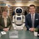 AI-generated image (GPT-2): Three very different library staff members, a traditional librarian, a friendly service robot, and a salesman-like attendant, compete for a visitor's attention at a public library help desk.