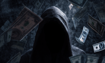 Closeup on a shadowy hooded figure, surrounded by floating cash.