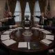 AI-generated article illustration (GPT-2): Politicians seated around a round conference table point at one another while shouting, with an industrial humanoid robot sitting motionless at the center of the room.