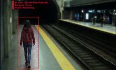 AI-generated image (GPT-2): A surveillance-style view of a subway platform showing a person walking near the platform edge, with an AI monitoring overlay displaying a detection box around the individual, a tunnel entrance ahead, and passengers visible on the opposite platform.