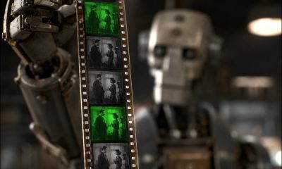 AI-generated image (GPT-2 + Photoshop): an industrial humanoid robot, heavily blurred, holds a vertical strip of 70mm film close to the camera, with the film frames in sharp focus showing a man and a woman standing and conversing. Every third frame is tinted green and the others appear monochrome.