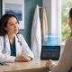Physician speaking with a patient as an AI medical scribe visualizes audio and draft notes above a tablet