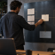 An operator updates a central reference card on a board connecting different business responsibilities.