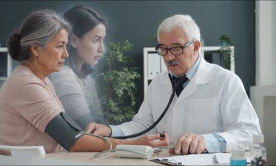 Image by Vitaly Gariev at Unsplash, altered by GPT Image 2.5 to generate an older woman and to turn the real younger woman into an apparition representing stale patient data. Source: https://unsplash.com/photos/doctor-checks-patients-blood-pressure-with-stethoscope-NDOYHZ_98Rw license source - https://unsplash.com/license