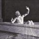 A vision of Archimedes shouting 'Eureka' as the dynamics of his bath inspire a new method of volume measurement. The image is outpainted laterally by GPT Image 2 in order to fit the format size, but the middle section is original and comes from https://math.nyu.edu/Archimedes/Crown/Vitruvius.html. The attribution there reads 'This illustration and text are from a magazine advertisement for NBC, probably dating from the 1940’s. It was found among the files of the Print and Picture Department of the Free Library of Philadelphia.'