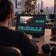 Creator desk with a laptop showing a video timeline and audio waveform