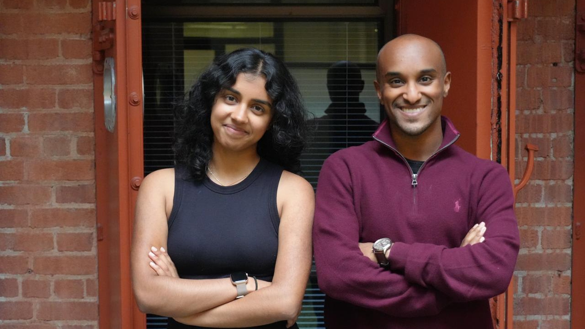 Colare co-founders Esther Thomas, left, and Nain Abdi, right, standing outside a brick building.