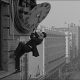 Harold Lloyd hangs from a clock face in Safety Last! (1923). The film is in the US public domain.. Source: https://www.youtube.com/watch?v=tzh4htLXp6Q
