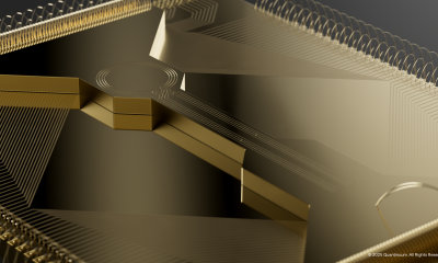 Close-up rendering of Quantinuum’s gold Helios ion-trap chip against a dark background