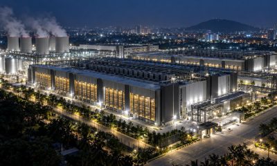 Data-centre campus at night with cooling towers and lit server halls