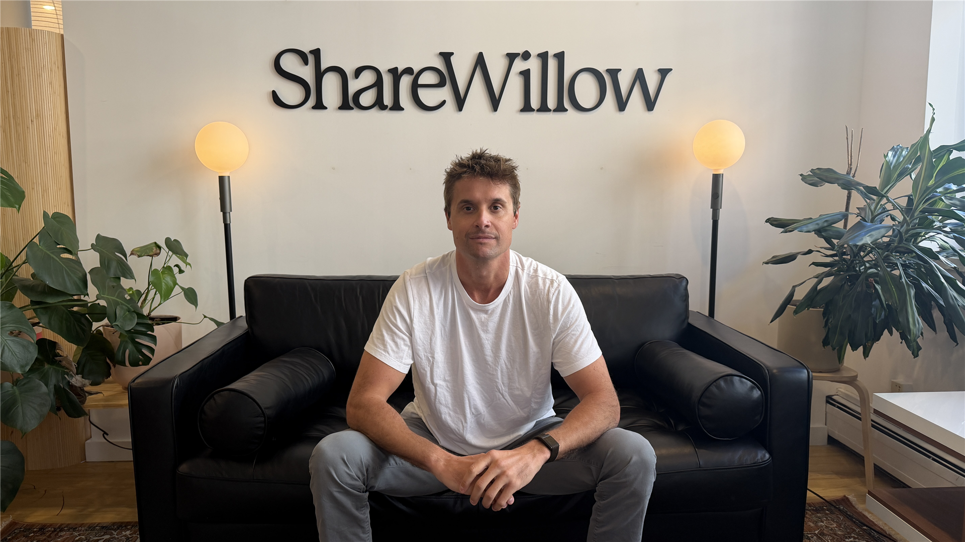 ShareWillow founder and CEO Ryan Shank seated beneath the company sign.