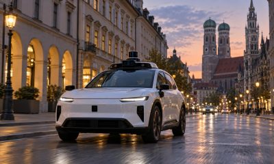 White driverless robotaxi on a European city street at dusk
