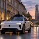White driverless robotaxi on a European city street at dusk