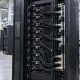 Black liquid-cooled server rack on a factory floor
